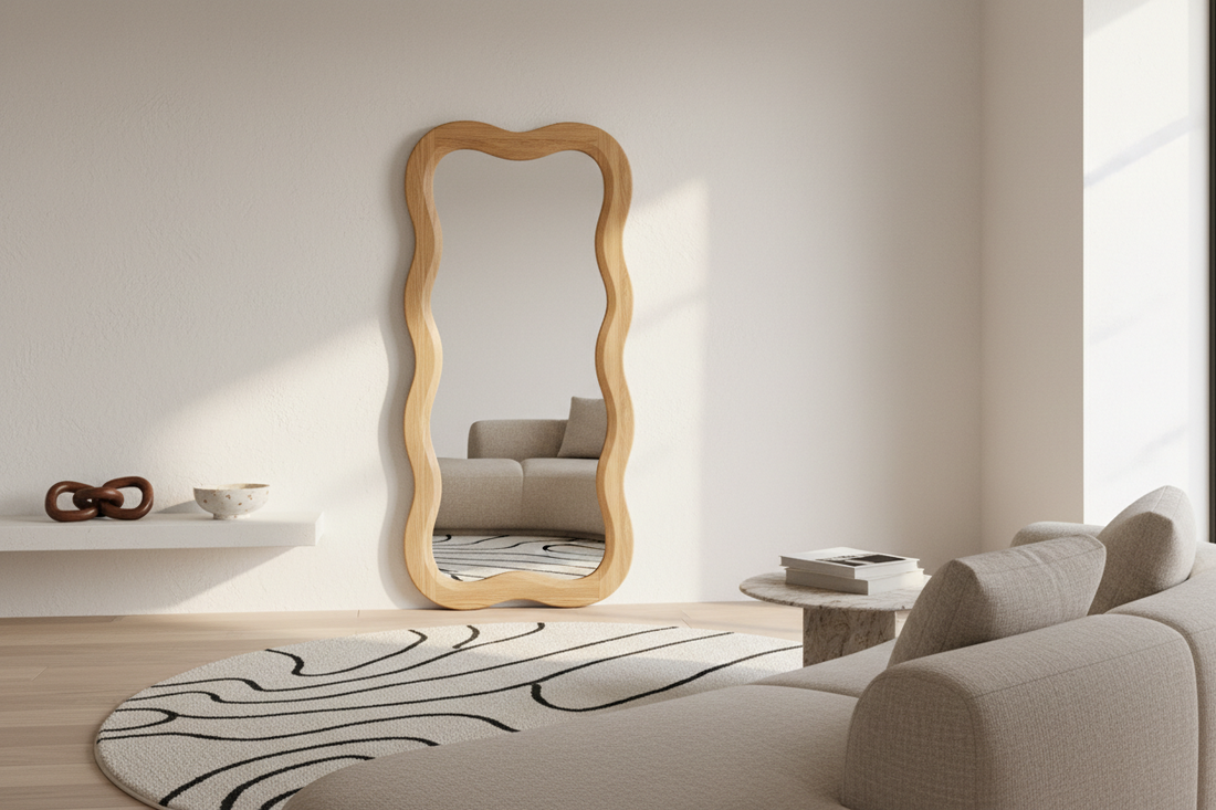 Beautifully styled modern living room with a wavy wooden-framed mirror, cream round rug with abstract black lines, and minimalist shelf decor — FitFlow home decor styling guide