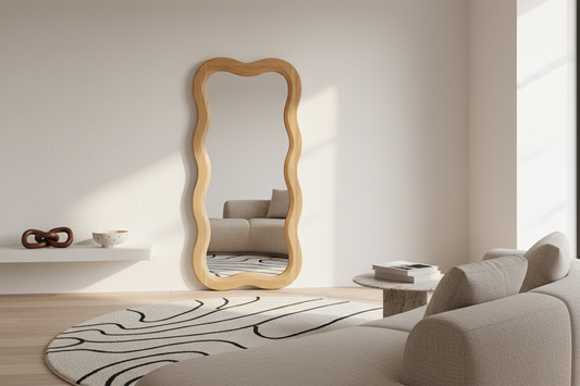 Beautifully styled modern living room with a wavy wooden-framed mirror, cream round rug with abstract black lines, and minimalist shelf decor — FitFlow home decor styling guide