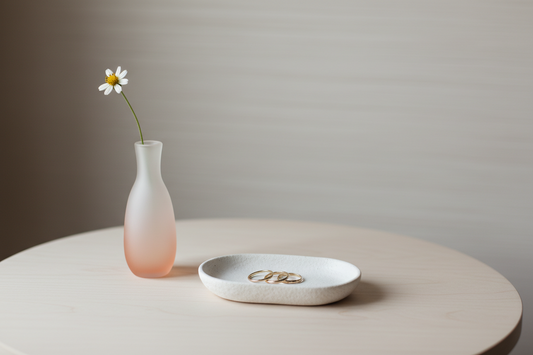A beautifully styled minimalist vanity featuring jewelry dishes and a gradient glass bud vase, by Fit-Flow.