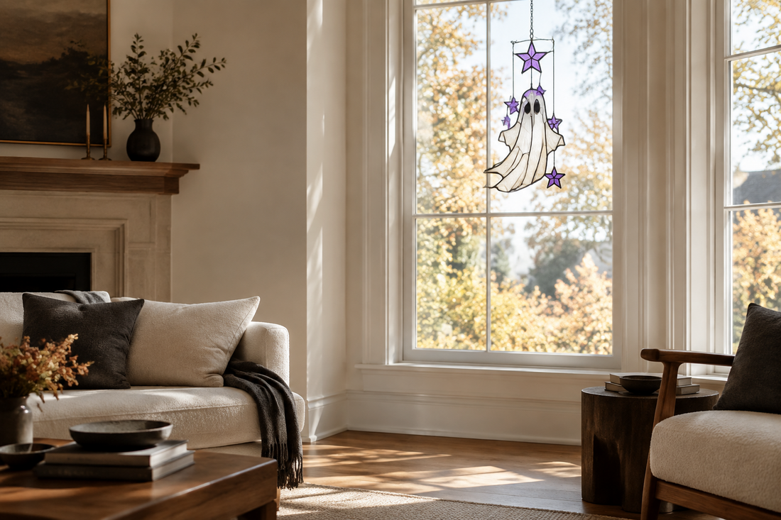 Ghost and purple stars stained-glass suncatcher in a sunlit minimalist living room window decorated for Halloween