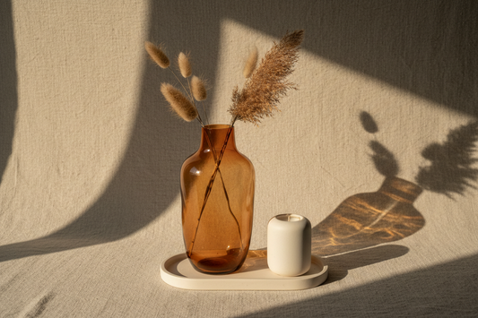 Late summer home refresh vignette with amber glass vase, white ceramic bud vase, and cream candle on a linen surface