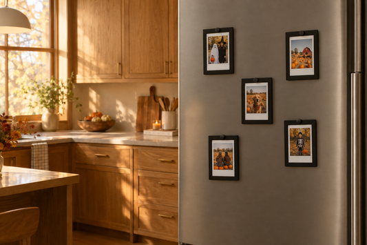 Five black magnetic Instax Mini frames displaying Halloween costume and pumpkin-patch photos on a refrigerator door.